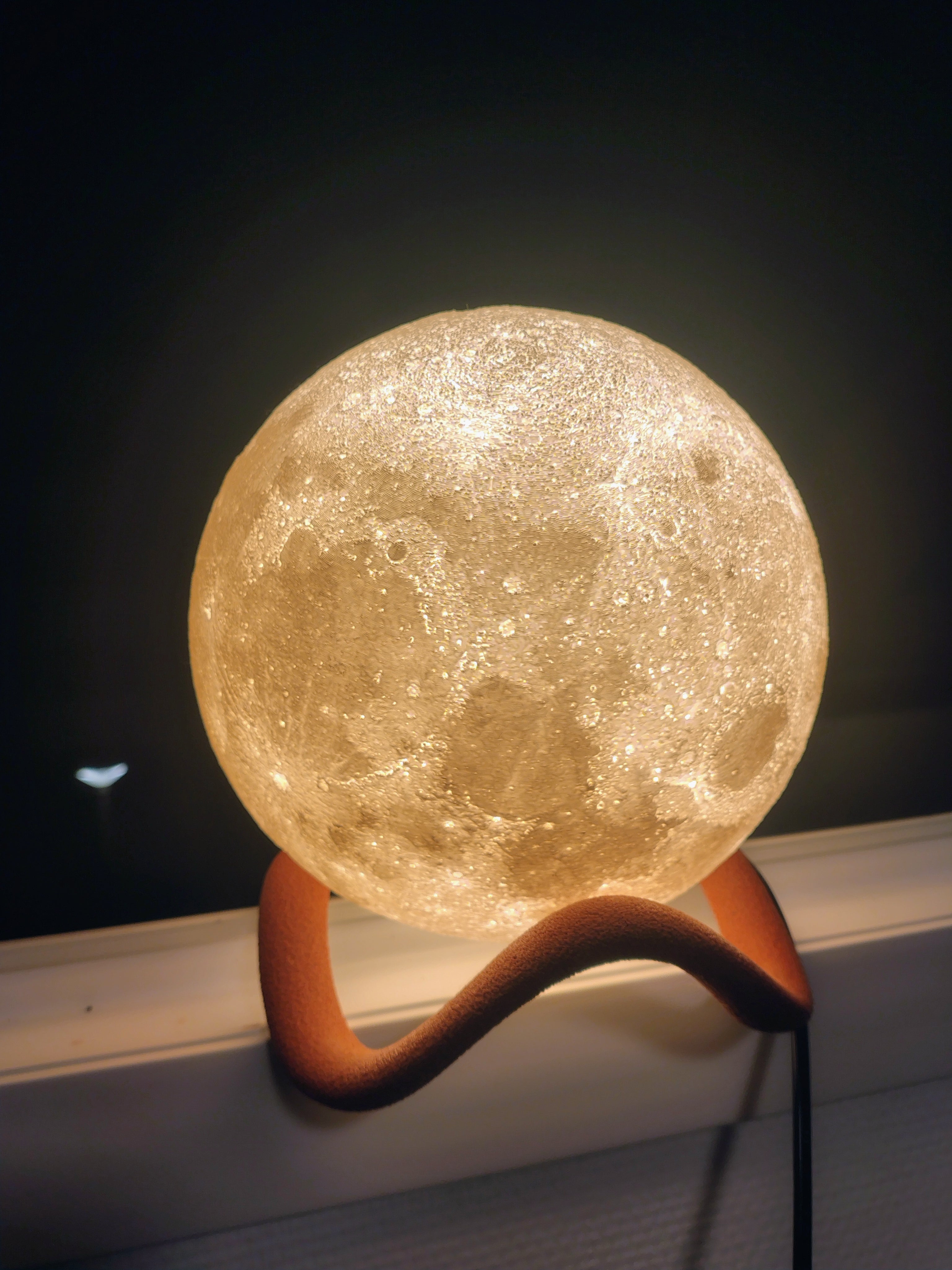 Lampe lune 3D réaliste lumineuse sur son socle, servant de veilleuse et décoration d'ambiance